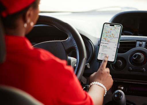 Une femme recherchant une station essence sur son téléphone, voiture à l'arrêt